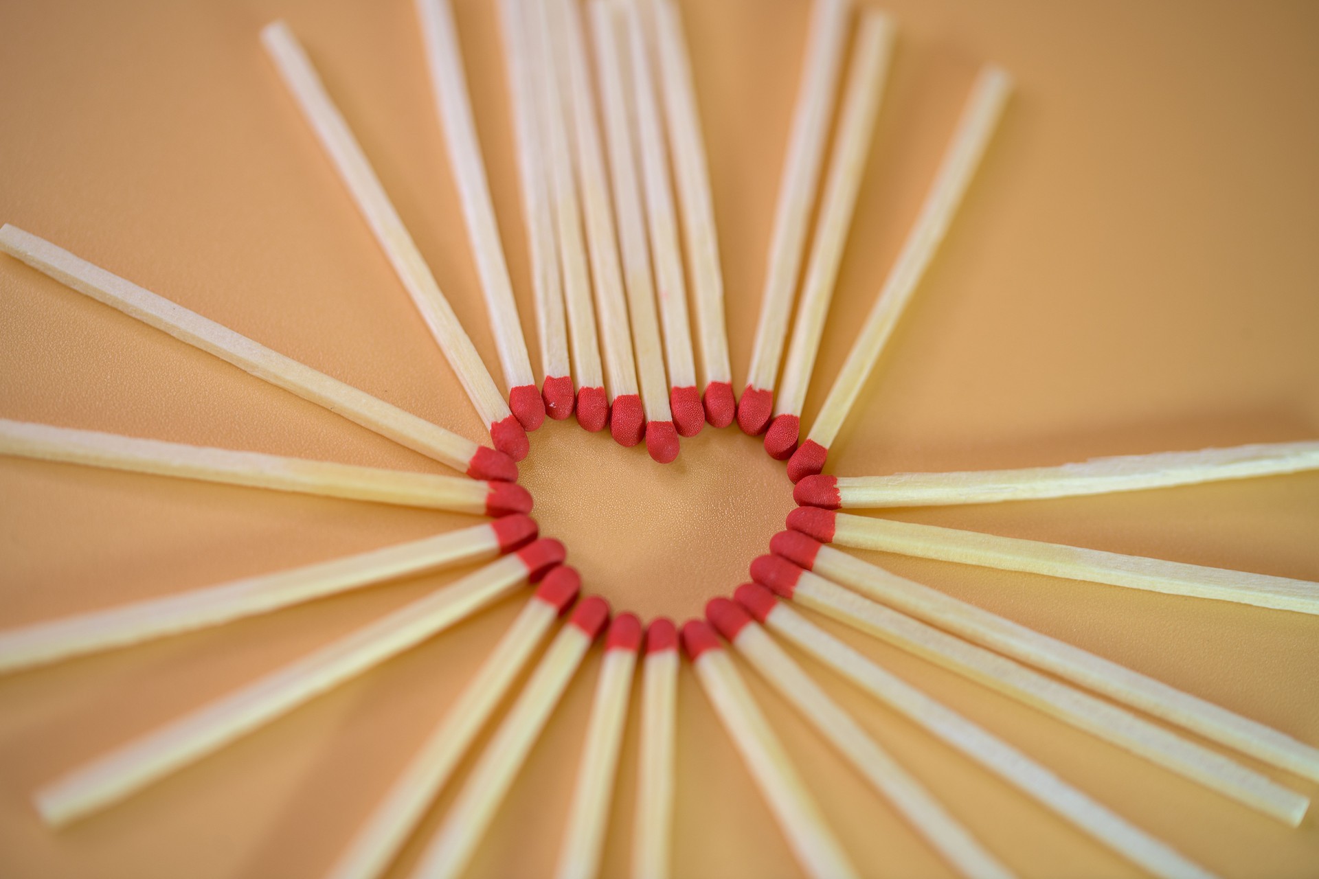 Heart Shape Made of Matchsticks on Warm Orange Background
