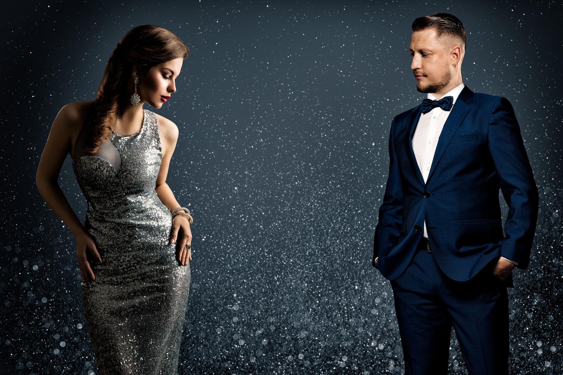 Fashion Luxury Couple. Glamour Woman and Handsome Man. Elegant Pair in evening Dress and Suit. Sparkling Background